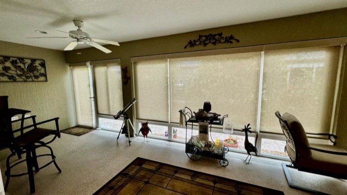 Solar roller shades on a wall of windows in a family room
