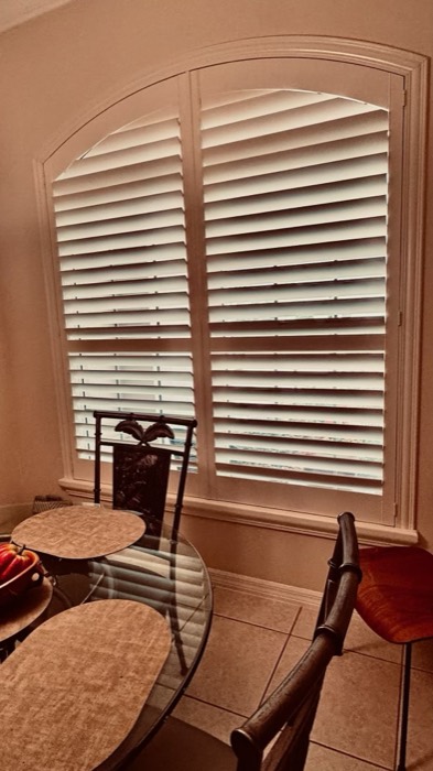 Arched-top plantation shutter on a living room window