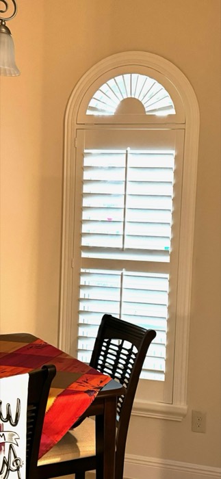 Elliptical arch plantation shutter with sunburst pattern above a dining window